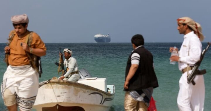 Hombres armados en la playa mientras el buque comercial Galaxy Leader, incautado por los hutíes de Yemen el mes pasado, está anclado frente a la costa de al-Salif
