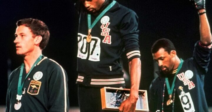 ohn Carlos y Tommie Smith con sus brazos en alto.